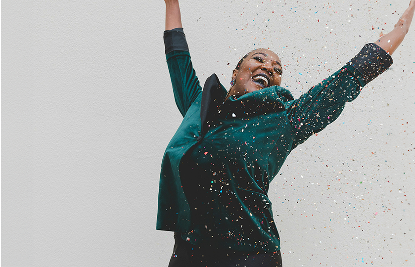 a woman jumping in joy surrounded with confetti / glitter