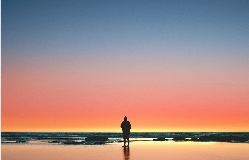 a person standing in front of the sea at sunset in solitude